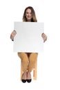 Businesswoman sitting holds a white bilboard and smiles