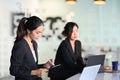 Businesswoman sitting in office with her colleague and writing business plan on notebook. Royalty Free Stock Photo