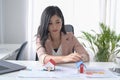 Businesswoman sitting in office with house model. Accounting, property investment concept.