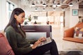 Businesswoman Sitting On Sofa Working On Laptop At Desk In Shared Workspace Office