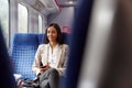 Businesswoman Sitting In Train Commuting To Work Checking Messages On Mobile Phone Royalty Free Stock Photo