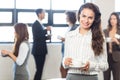 Businesswoman smiling at camera while her colleagues standing in background Royalty Free Stock Photo