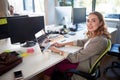 Businesswoman smiling at her desk while working on a computer. Happy woman at work typing and having a coffee Royalty Free Stock Photo