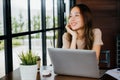 businesswoman smiling sitting alone at cafe desk with laptop computer she looking out of window Royalty Free Stock Photo