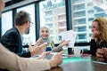 The businesswoman standing behind the desk while he sitting om the of desk