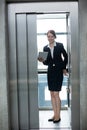 Businesswoman standing in an elevator holding a digital tablet Royalty Free Stock Photo