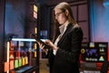 Businesswoman standing near glass office wall, using tablet computer