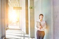 Businesswoman standing in office hall while holding document with yellow lens flare in background Royalty Free Stock Photo