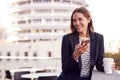 Businesswoman Standing Outside Office Building Using Mobile Phone With City Skyline In Background Royalty Free Stock Photo