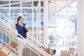 Businesswoman standing on stairs in bright office space with pho Royalty Free Stock Photo