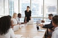 Businesswoman Stands To Address Meeting Around Board Table