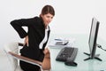 Businesswoman suffering from backache at computer desk