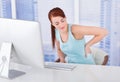 Businesswoman suffering from backache at computer desk