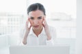 Businesswoman suffering from headache in front of laptop Royalty Free Stock Photo