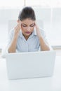 Businesswoman suffering from headache with laptop at office Royalty Free Stock Photo