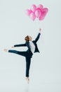 businesswoman in suit and ballet shoes holding pink balloons