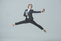 businesswoman in suit and ballet shoes jumping with coffee and tablet
