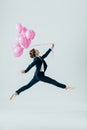 businesswoman in suit and ballet shoes jumping with pink balloons