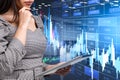 Businesswoman with tablet in hands, hologram with stock market chart