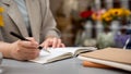 A businesswoman taking notes or writing something in her book while working remotely at a cafe Royalty Free Stock Photo