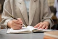 A businesswoman taking notes or writing something in her book while working remotely at a cafe Royalty Free Stock Photo