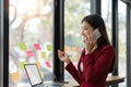 businesswoman talking on cellphone and work with laptop, writing notes on colorful sticky papers in office, consulting