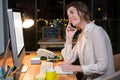 Businesswoman talking on mobile phone while working on computer at her desk Royalty Free Stock Photo