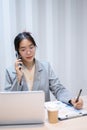 A businesswoman is talking on the phone, taking notes, and reading information on her laptop Royalty Free Stock Photo