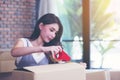 Businesswoman taping up a cardboard box, Asian woman packing boxes among stack of parcels in her shopping online business at home