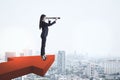 Businesswoman with telescope standing on red arrow