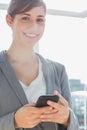 Businesswoman texting on smartphone and smiling at camera Royalty Free Stock Photo