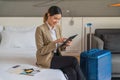 Businesswoman traveller sitting on bed using computer tablet in hotel room Royalty Free Stock Photo