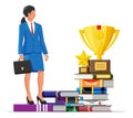 Businesswoman with trophy on stack of books.