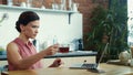 Businesswoman typing on computer in kitchen. Female freelancer finishing work.