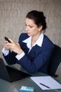Businesswoman typing message on phone in office