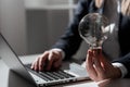 Businesswoman Typing Recent Updates On Lap Top On Desk Holding Lightbulb. Woman In Office Writing Important Message On