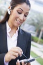 Businesswoman using bluetooth earpiece and PDA