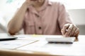 Businesswoman is using a calculator to check the numbers on a company financial document during a meeting with shareholders.