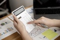 Businesswoman is using a calculator to check the numbers on a company financial document during a meeting with shareholders.