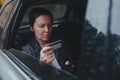 Businesswoman using credit card and mobile smart phone for e-banking from backseat of the car Royalty Free Stock Photo