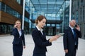 Businesswoman using digital tablet while colleagues talking on mobile phone Royalty Free Stock Photo