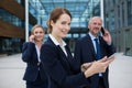 Businesswoman using digital tablet while colleagues talking on mobile phone Royalty Free Stock Photo