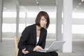 Businesswoman Using Laptop On Chair In Empty Warehouse Royalty Free Stock Photo