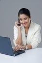 Businesswoman using laptop and talking on a mobile phone