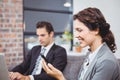 Businesswoman using mobile phone while colleague working Royalty Free Stock Photo