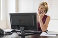 Businesswoman Using Mobile Phone At Computer Desk Royalty Free Stock Photo