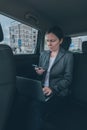 Businesswoman using mobile phone and laptop computer in car Royalty Free Stock Photo