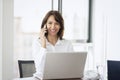 Businesswoman using mobile phone and laptop while working at office desk Royalty Free Stock Photo