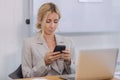 businesswoman using mobile phone sitting at table office. female chatting message typing on smartphone in office Royalty Free Stock Photo