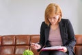 Woman using pen filling survey form on document in her hands while sitting on sofa at office. Accountant young woman Royalty Free Stock Photo